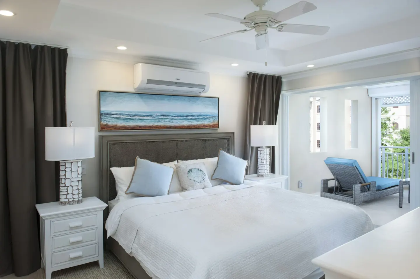 King bedroom with ceiling fan and balcony alcove in a suite at The Crane Resort.