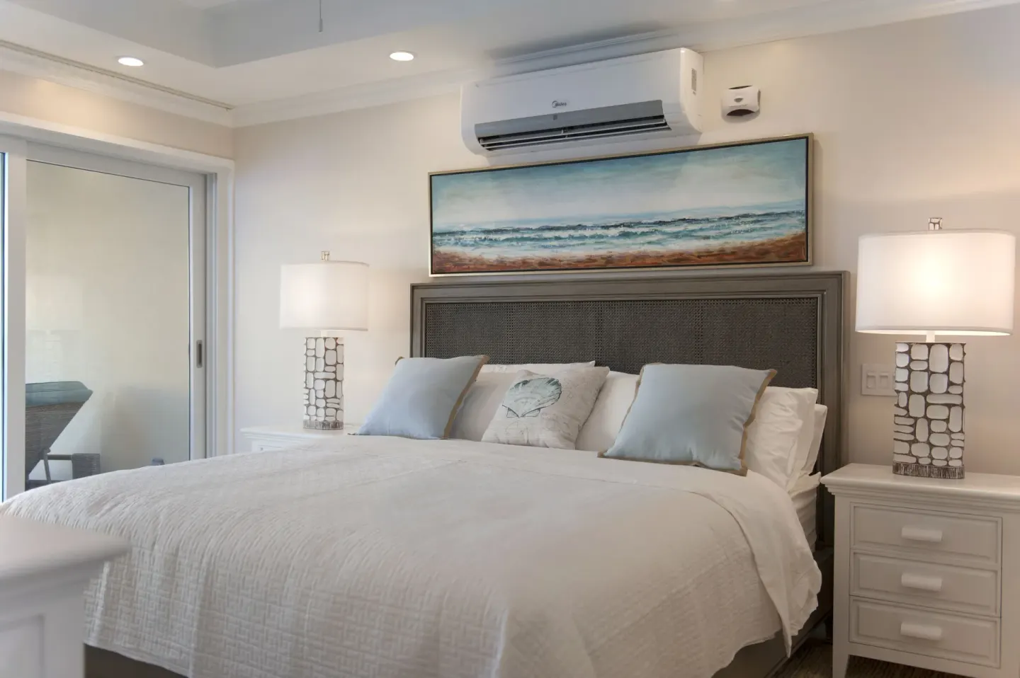 King bed with bedside lamps and ocean artwork in a two-bedroom suite at The Crane Resort.