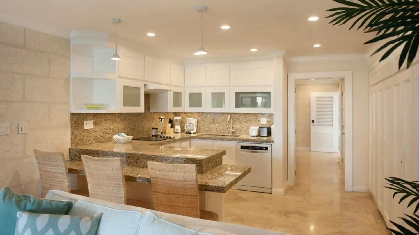 Suite kitchen with granite breakfast bar and white cabinetry at The Crane Resort.
