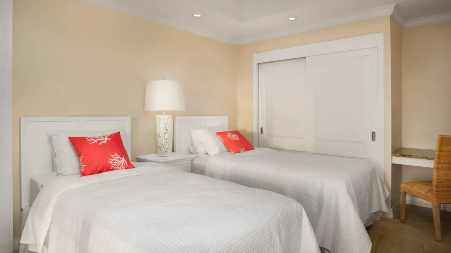 Twin bedroom with two beds and coral pillows in a two-bedroom suite at The Crane Resort.