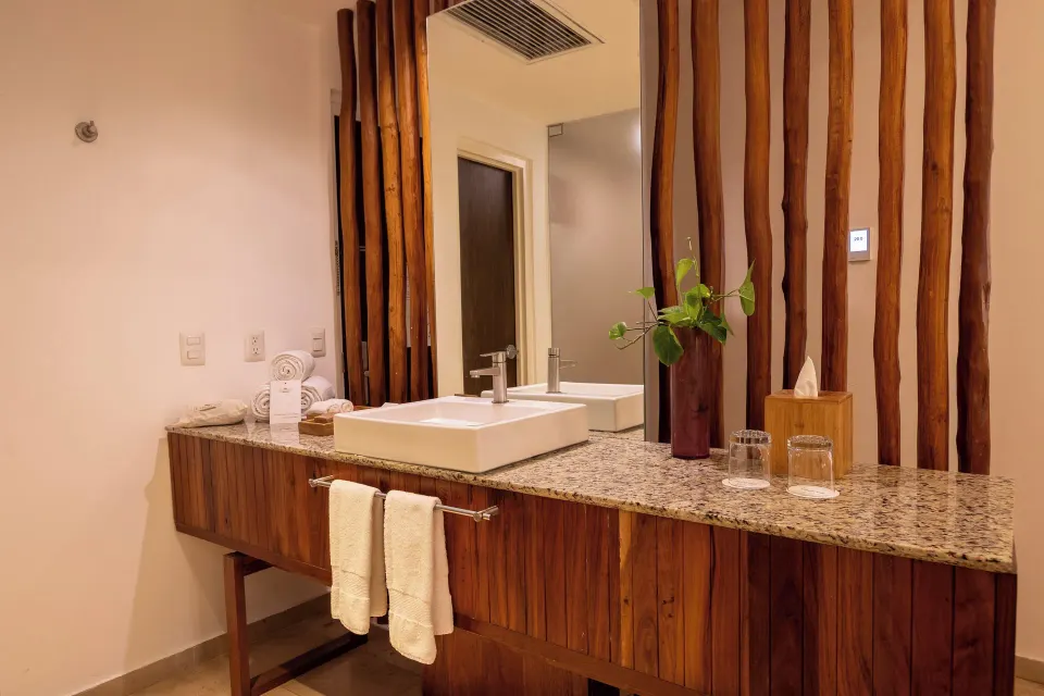 Granite countertop vanity with towel rails and decorative vase at The Explorean Cozumel