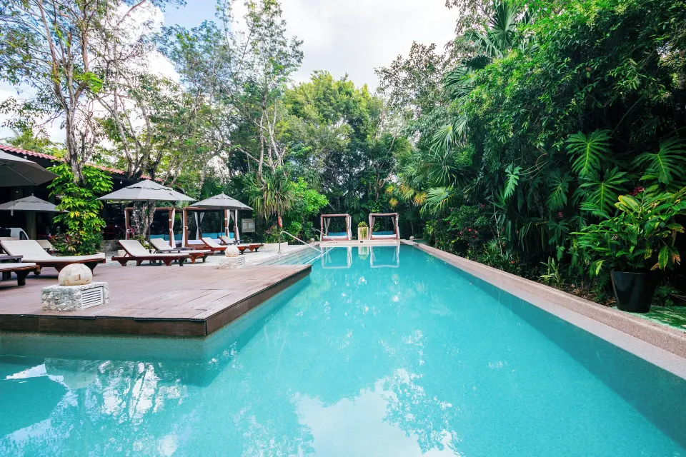 Long swimming pool flanked by loungers, cabanas and jungle foliage at The Explorean Cozumel