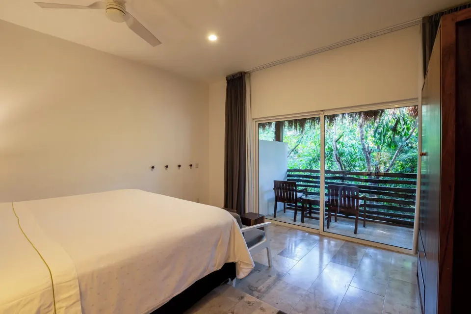 Spacious guest room interior with king bed and balcony at The Explorean Cozumel