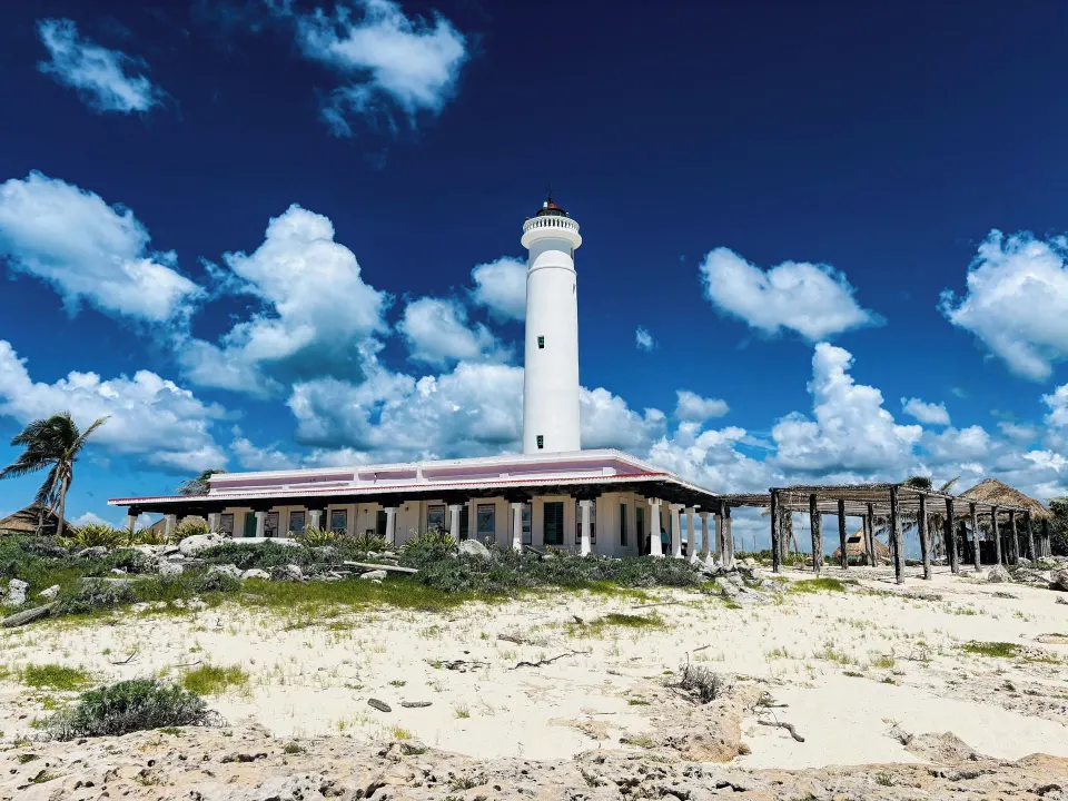 White lighthouse and low building on a sandy point near The Explorean Cozumel