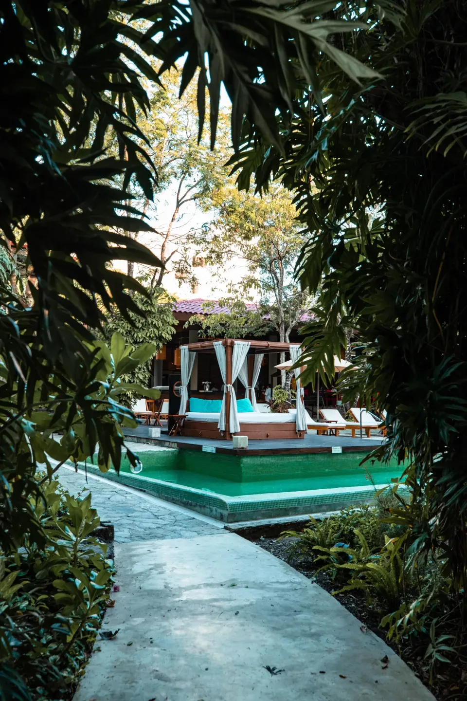 Pathway framed by foliage leading to cabanas on an elevated pool deck at The Explorean Cozumel
