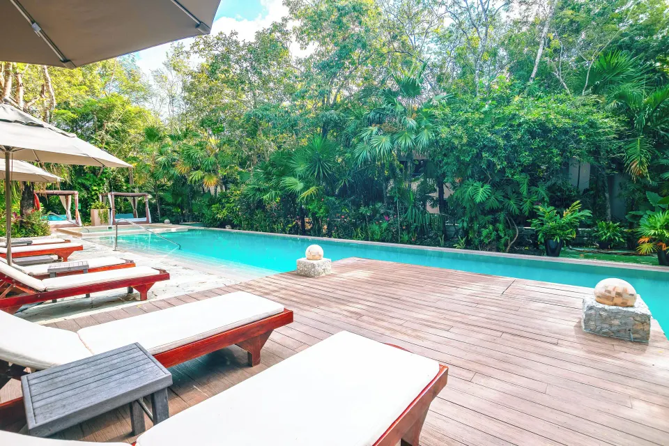 Resort pool deck with padded loungers and tropical foliage at The Explorean Cozumel