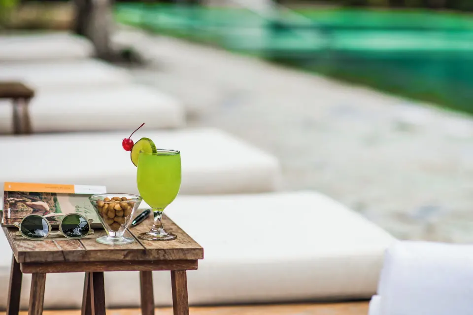 Cocktail and snacks on a small table beside poolside loungers at The Explorean Cozumel