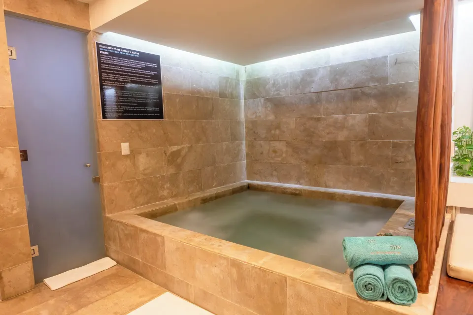 Indoor tiled spa soaking tub with rolled towels in a treatment area at The Explorean Cozumel