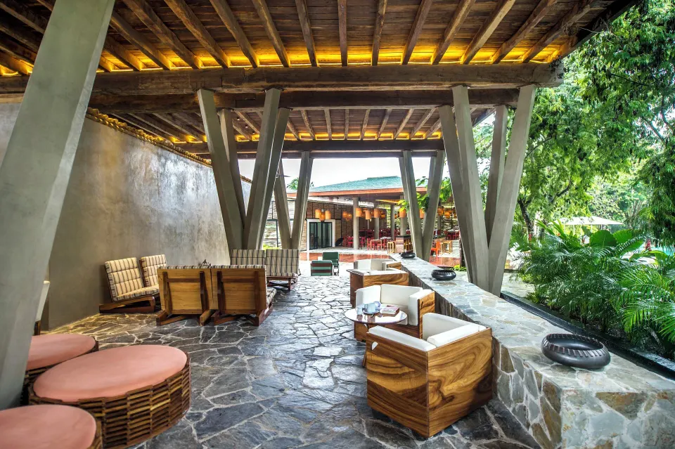 Shaded open-air lounge with wooden furniture and stone floor at The Explorean Cozumel