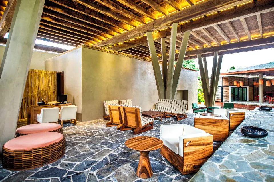 Daytime covered terrace lounge with woven seating and wooden tables at The Explorean Cozumel