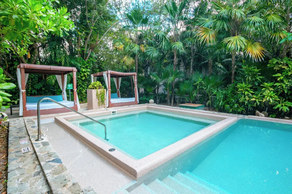 Series of small connected spa pools and cabanas surrounded by palms at The Explorean Cozumel