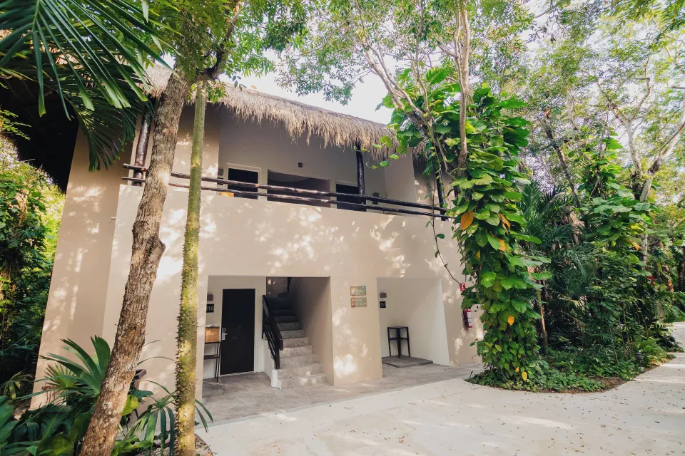 Two-story beige villa building surrounded by tropical plants at The Explorean Cozumel