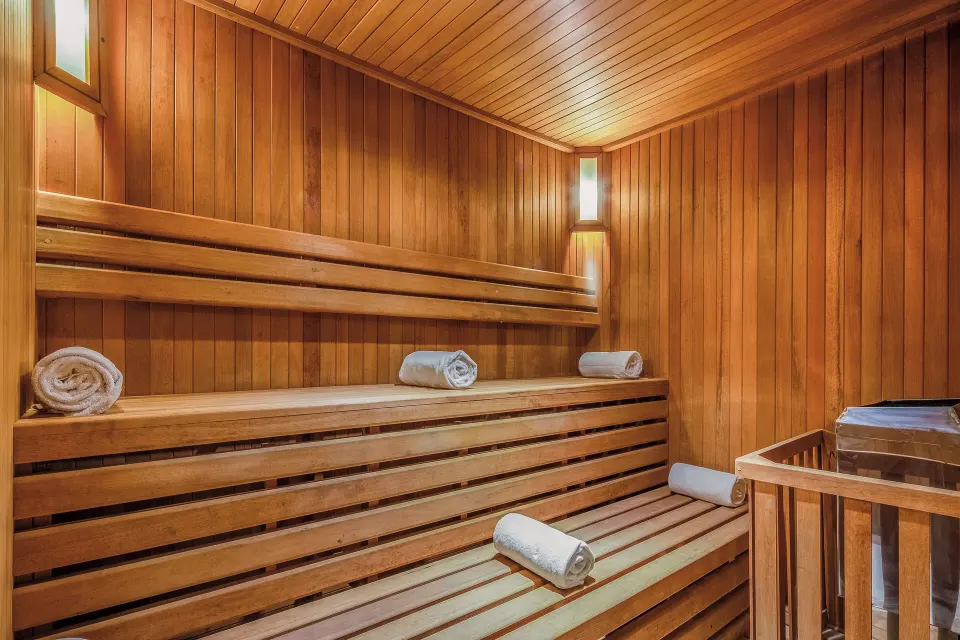 Wood-panelled sauna with tiered benches and rolled towels at The Explorean Cozumel
