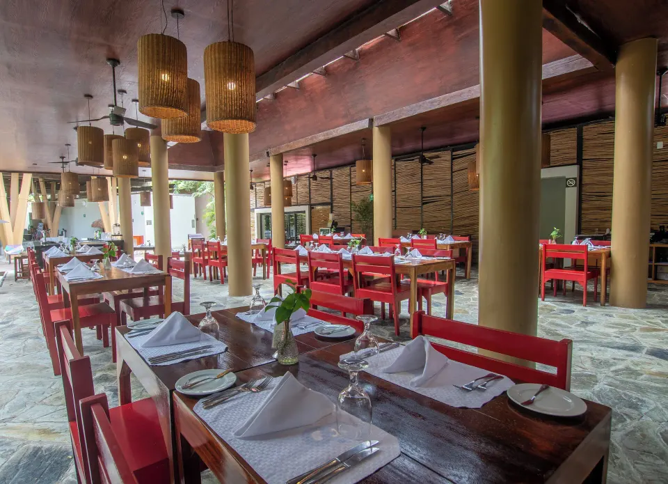 Set tables with red chairs and pendant lights in the resort restaurant at The Explorean Cozumel