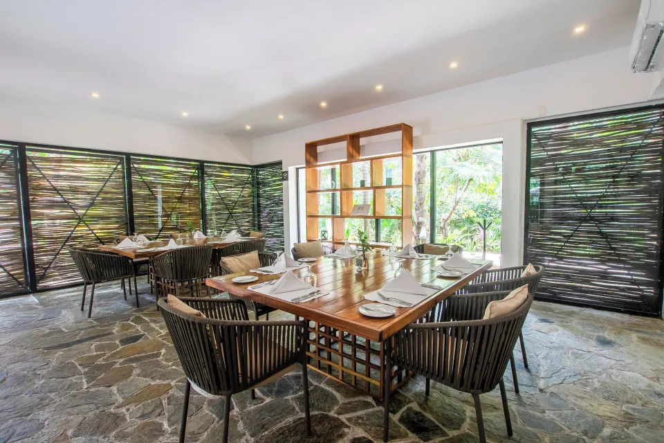 Indoor dining table set with wicker chairs at The Explorean Cozumel