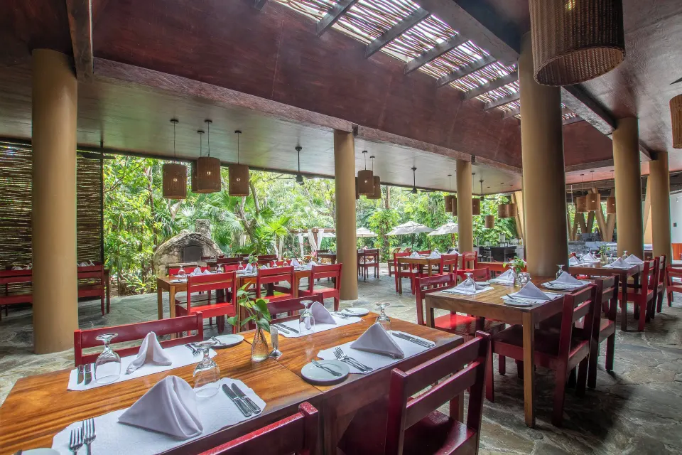 Open-air restaurant seating with red benches and wooden tables at The Explorean Cozumel