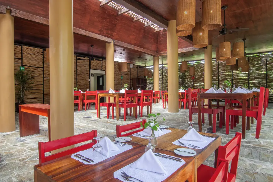 Open-air restaurant dining room with red chairs and stone floor at The Explorean Cozumel
