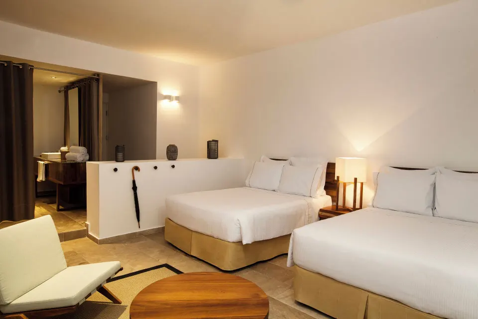 Casita Stand Alone evening view showing two beds and open bathroom area at The Explorean Cozumel.