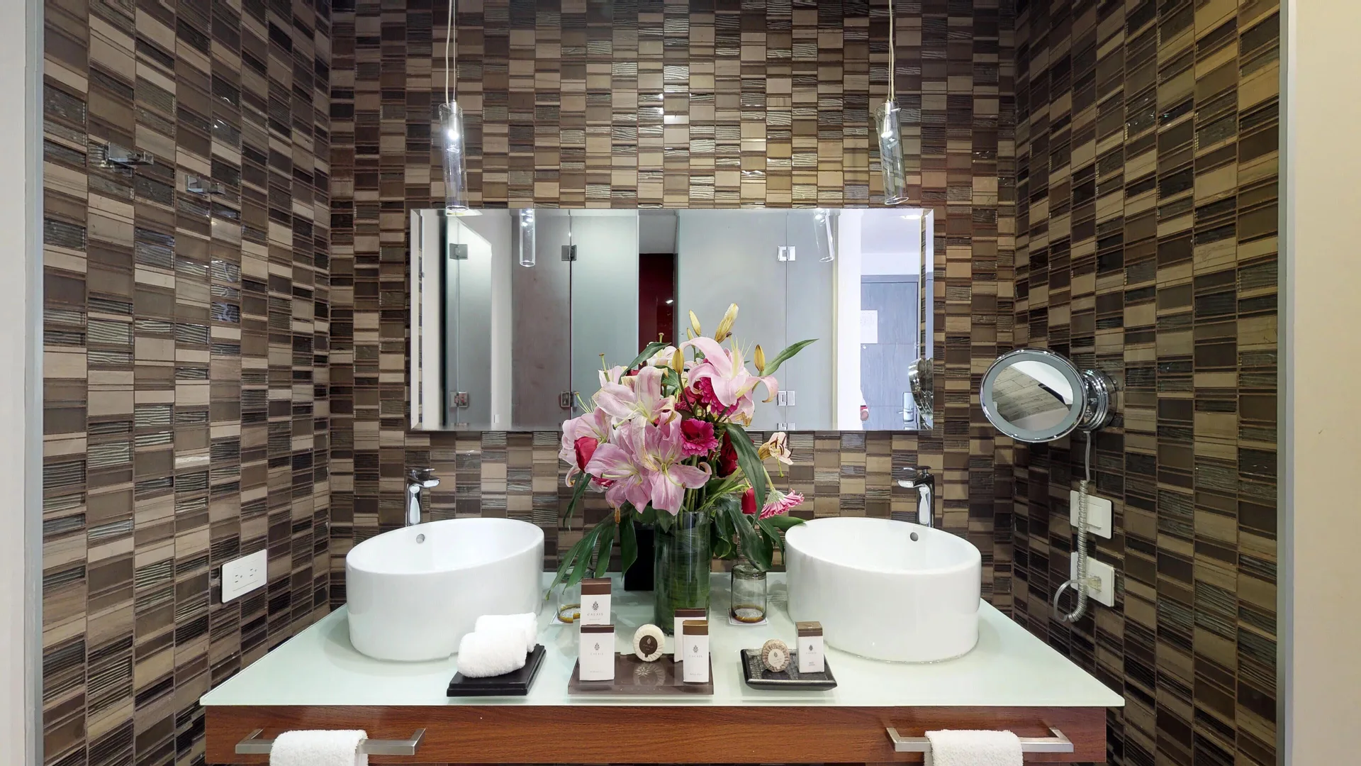 Double vanity bathroom with flowers and mosaic tile at The Fives Beach Hotel.