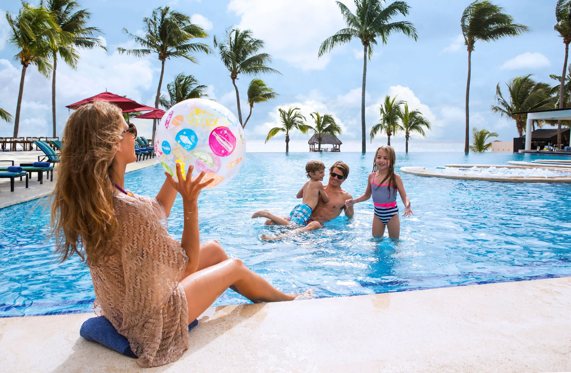 Family playing with a beach ball in the oceanfront pool at The Fives Beach Hotel.