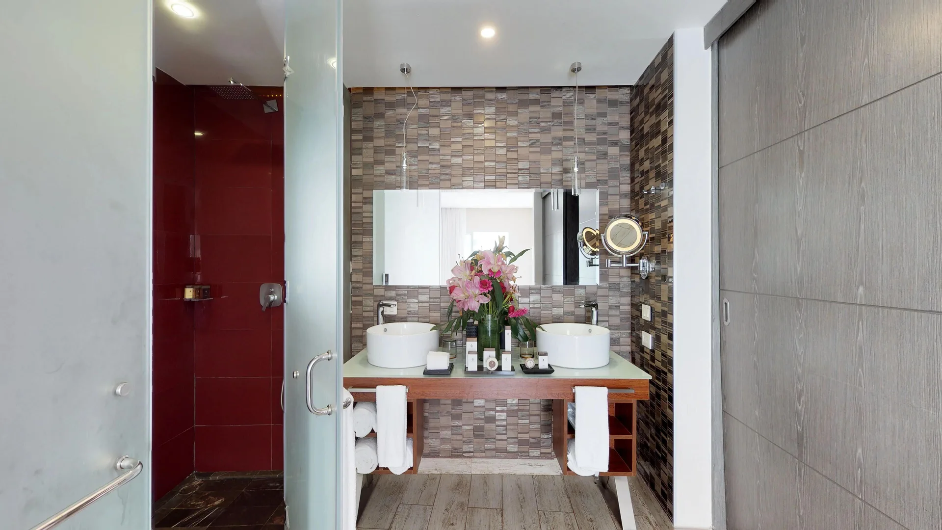 Guest bathroom with double sinks, glass shower, and red tile wall at The Fives Beach Hotel.