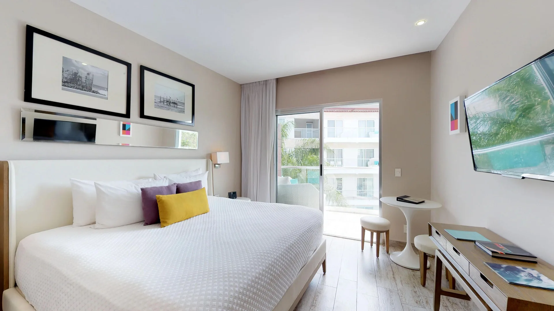 King-bed guest room with TV, desk, and balcony at The Fives Beach Hotel.