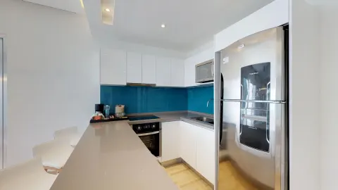 Guest suite kitchen with blue backsplash and refrigerator at The Fives Beach Hotel.