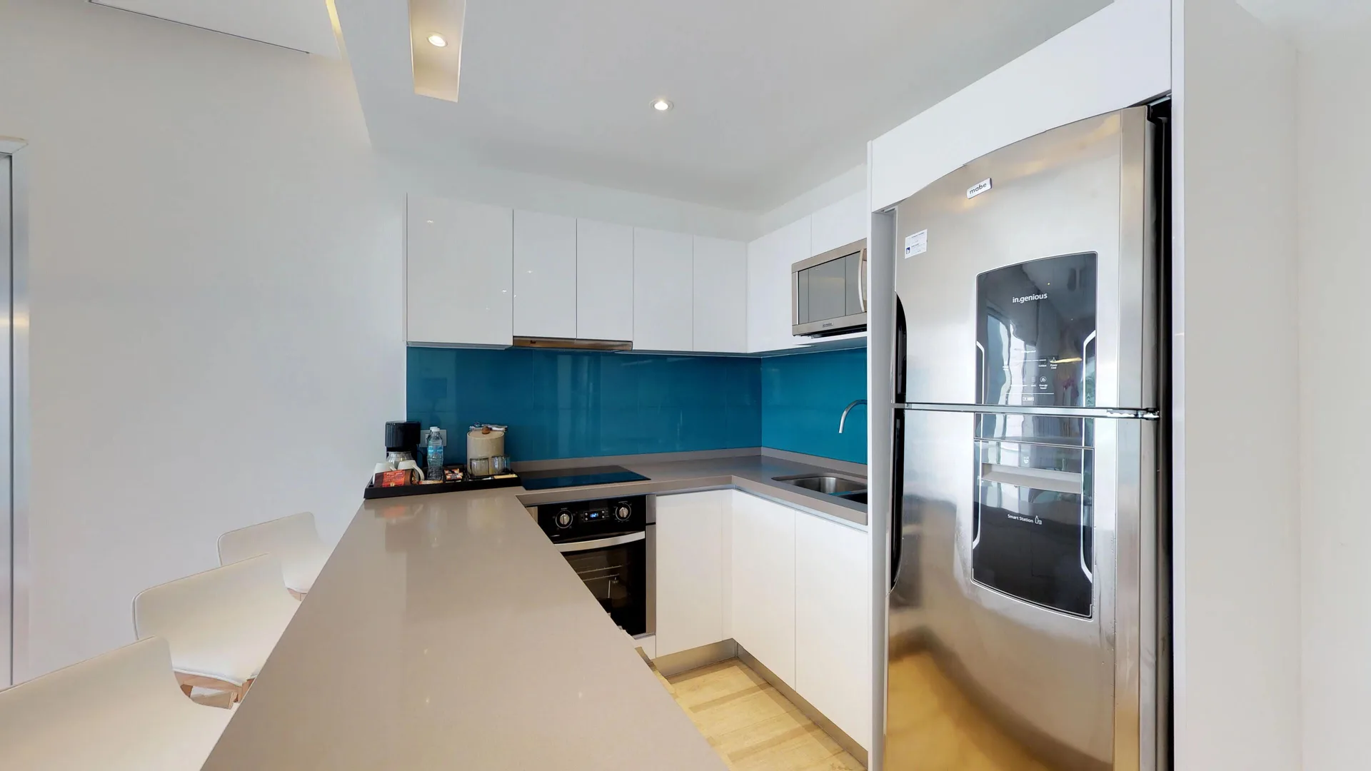 Guest suite kitchen with blue backsplash and refrigerator at The Fives Beach Hotel.