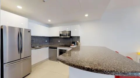 Guest suite kitchen with granite counter and stainless refrigerator at The Fives Beach Hotel.