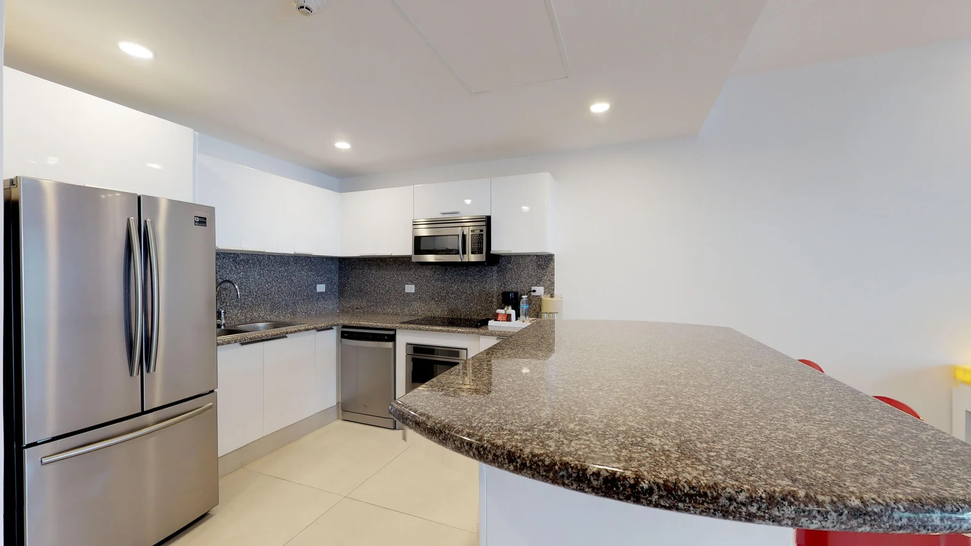 Guest suite kitchen with granite counter and stainless refrigerator at The Fives Beach Hotel.