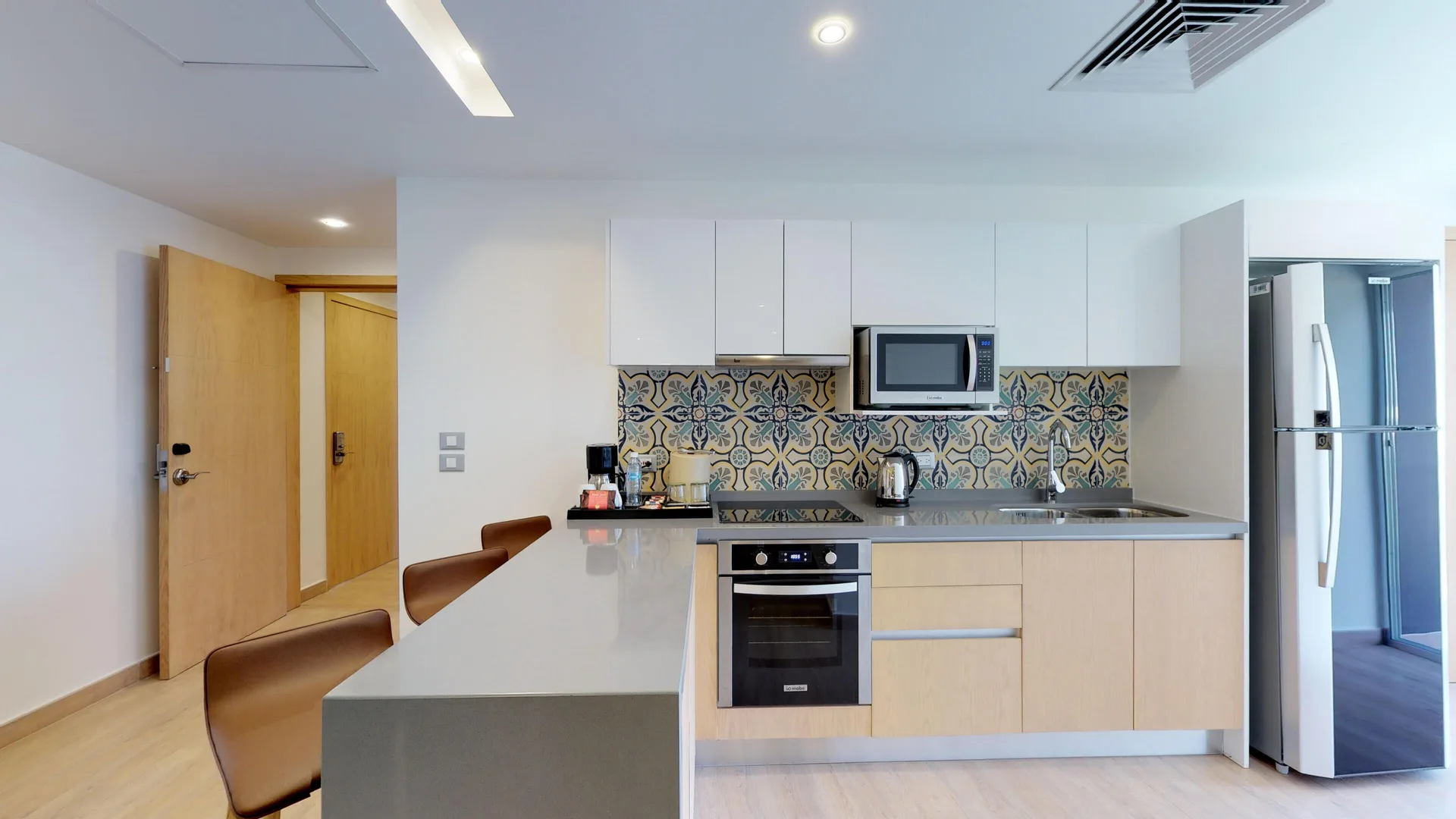 Guest suite kitchenette with patterned tile backsplash at The Fives Beach Hotel.