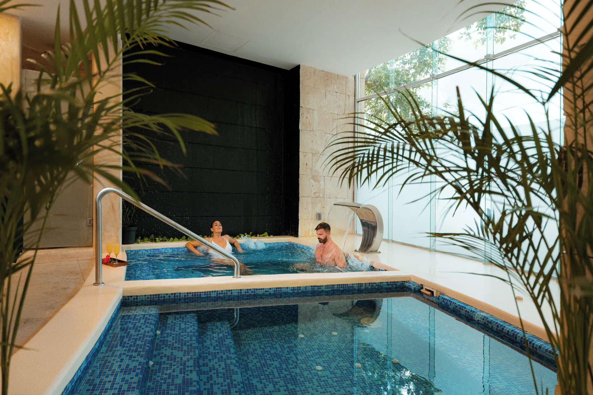 Guests relax in an indoor hydrotherapy pool area at The Fives Beach Hotel.