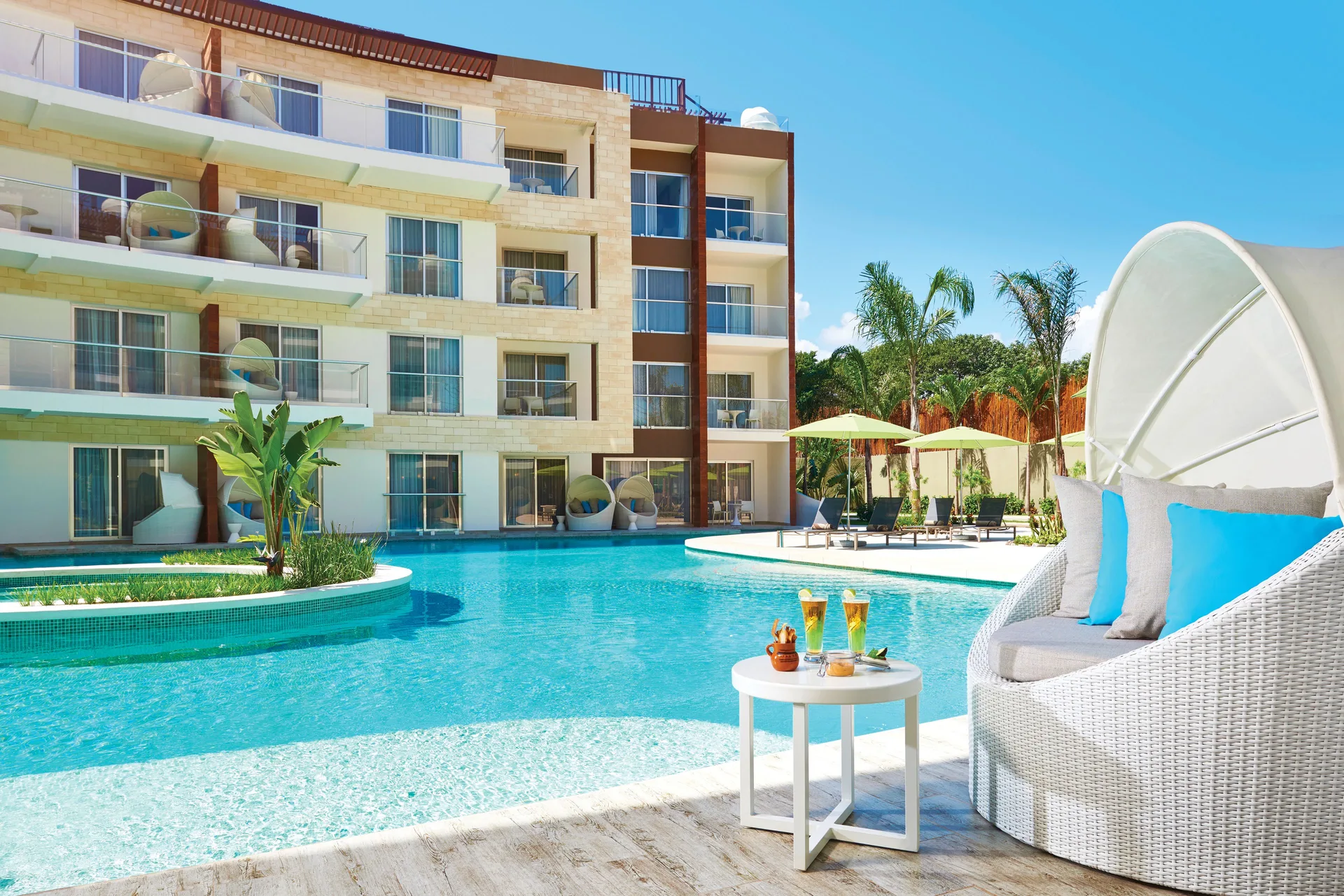 Poolside lounge chair facing a resort building and swim-up area at The Fives Beach Hotel.