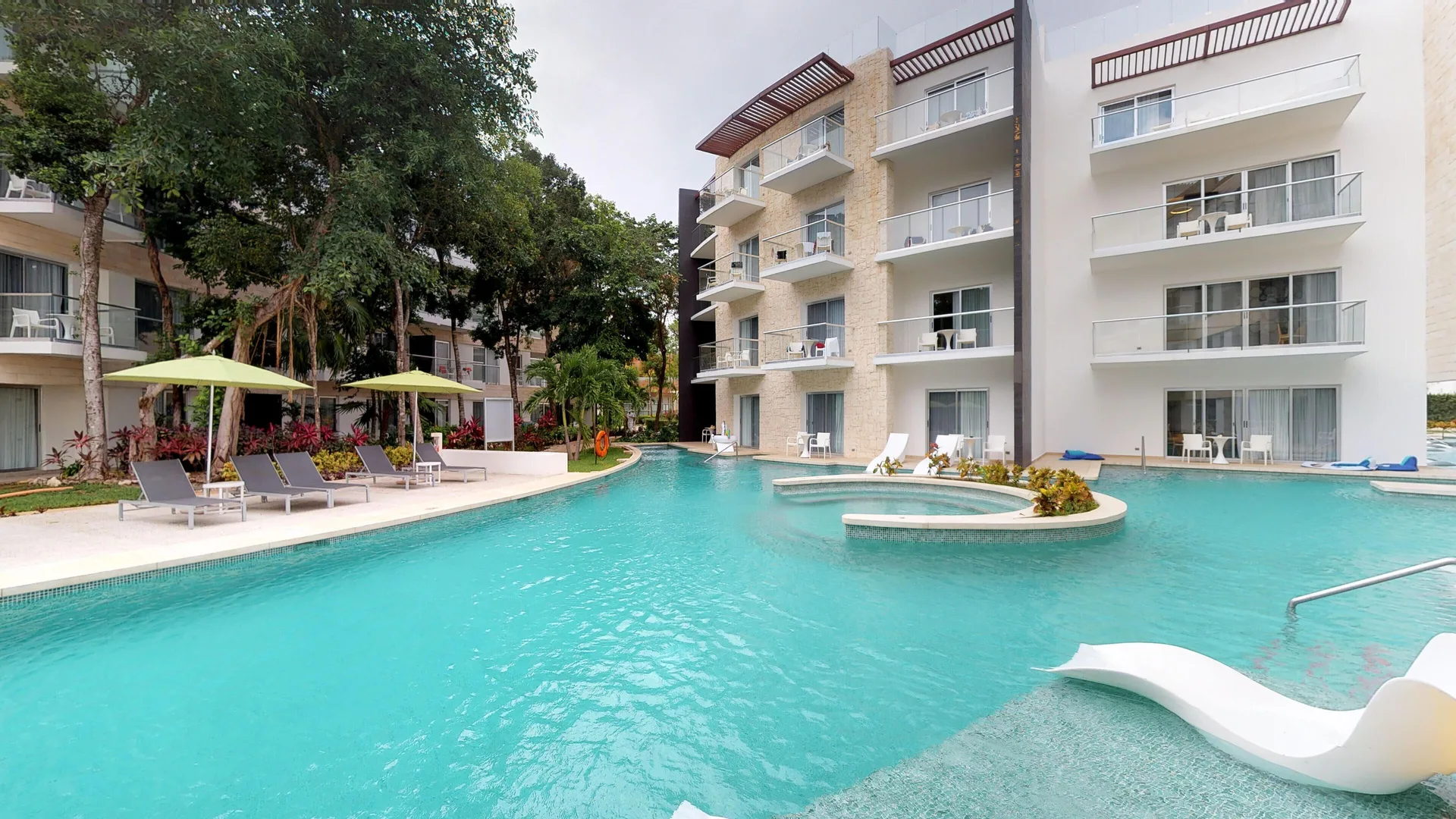 Resort pool with loungers, umbrellas, balconies, and white buildings at The Fives Beach Hotel.