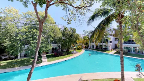 Curving pool bordered by trees and guest buildings at The Fives Beach Hotel.