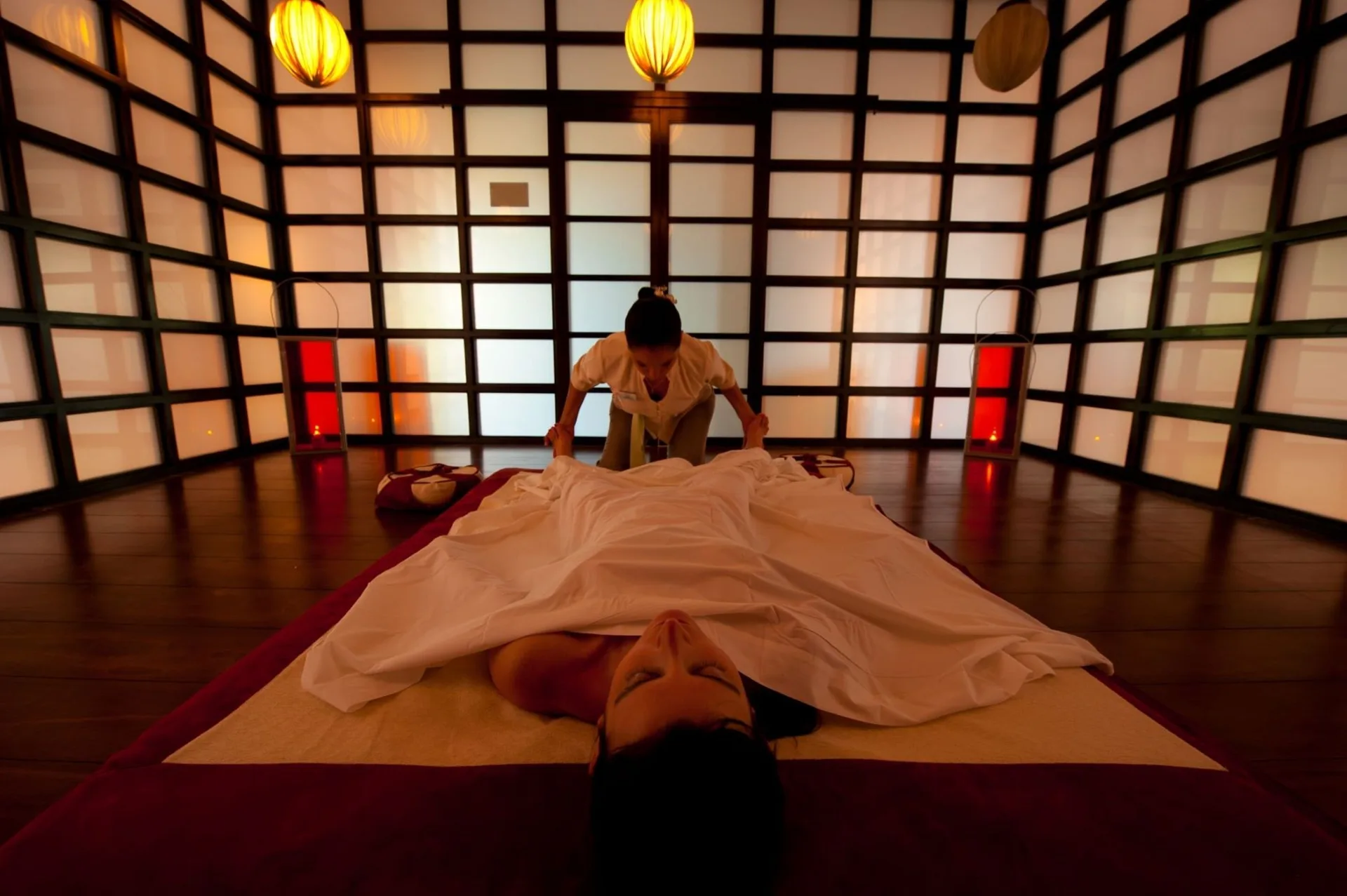 A spa therapist gives a massage in a softly lit treatment room at The Fives Beach Hotel.