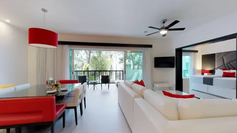 Suite living area with king bed visible and balcony at The Fives Beach Hotel.