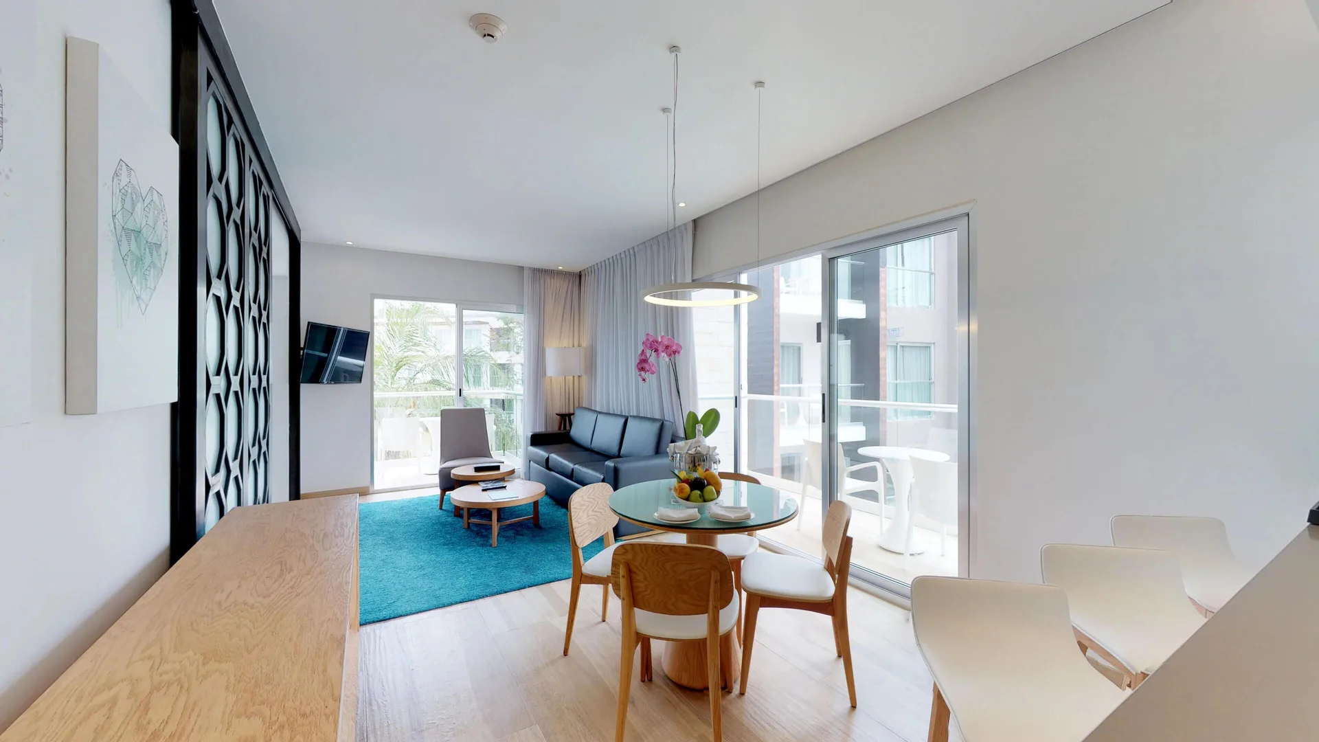 Bright suite living and dining area with balcony at The Fives Beach Hotel.