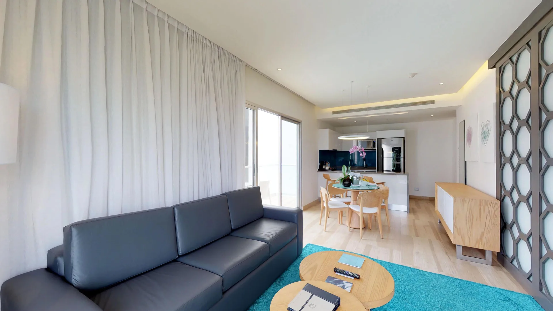 Suite living room with sofa, dining table, and kitchenette at The Fives Beach Hotel.