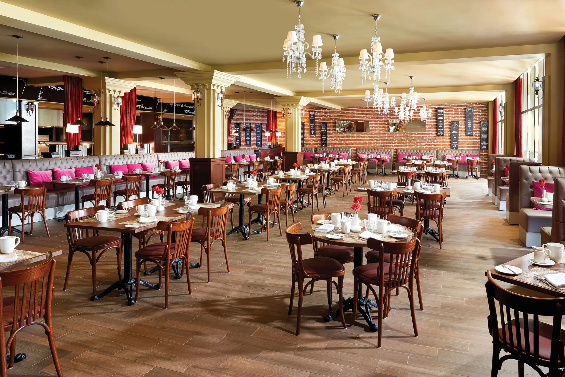 Bright restaurant dining room with set tables and chandeliers at The Fives Beach Hotel.