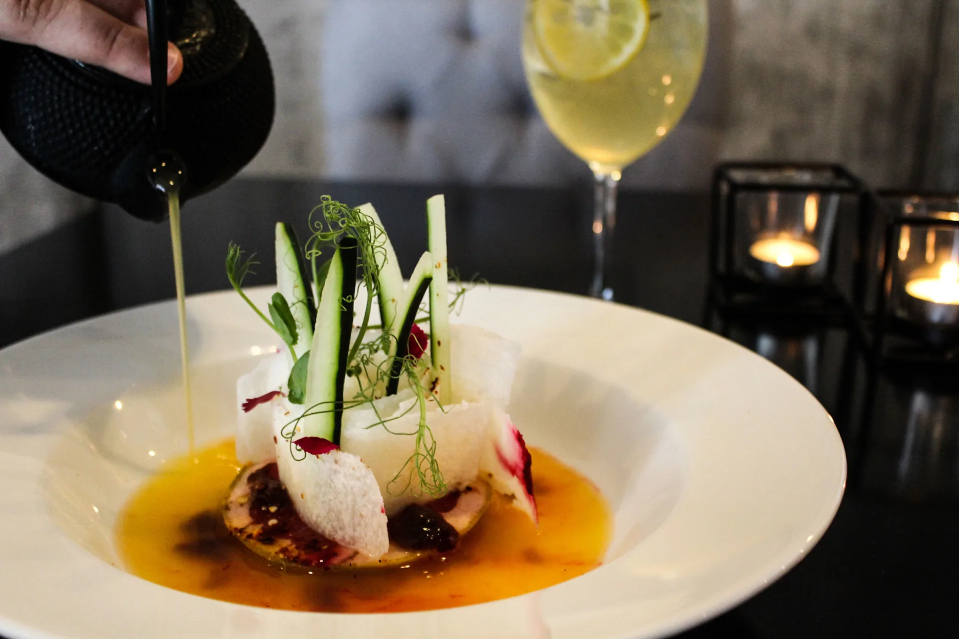 Broth being poured over a plated appetizer at The Fives Beach Hotel.