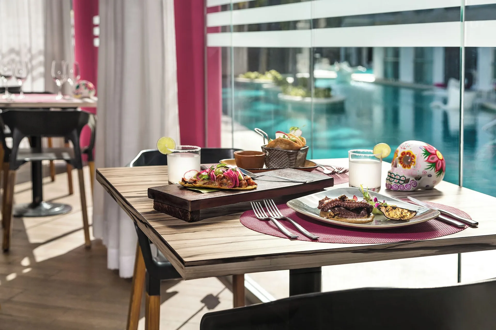 Mexican dishes and drinks on a poolside restaurant table at The Fives Beach Hotel.