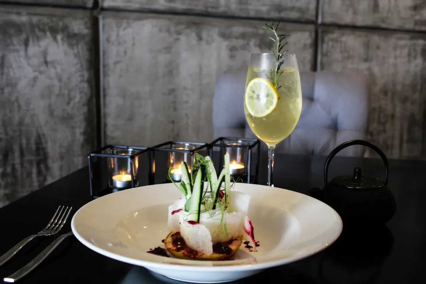 Plated appetizer with a citrus drink and candlelight at The Fives Beach Hotel.