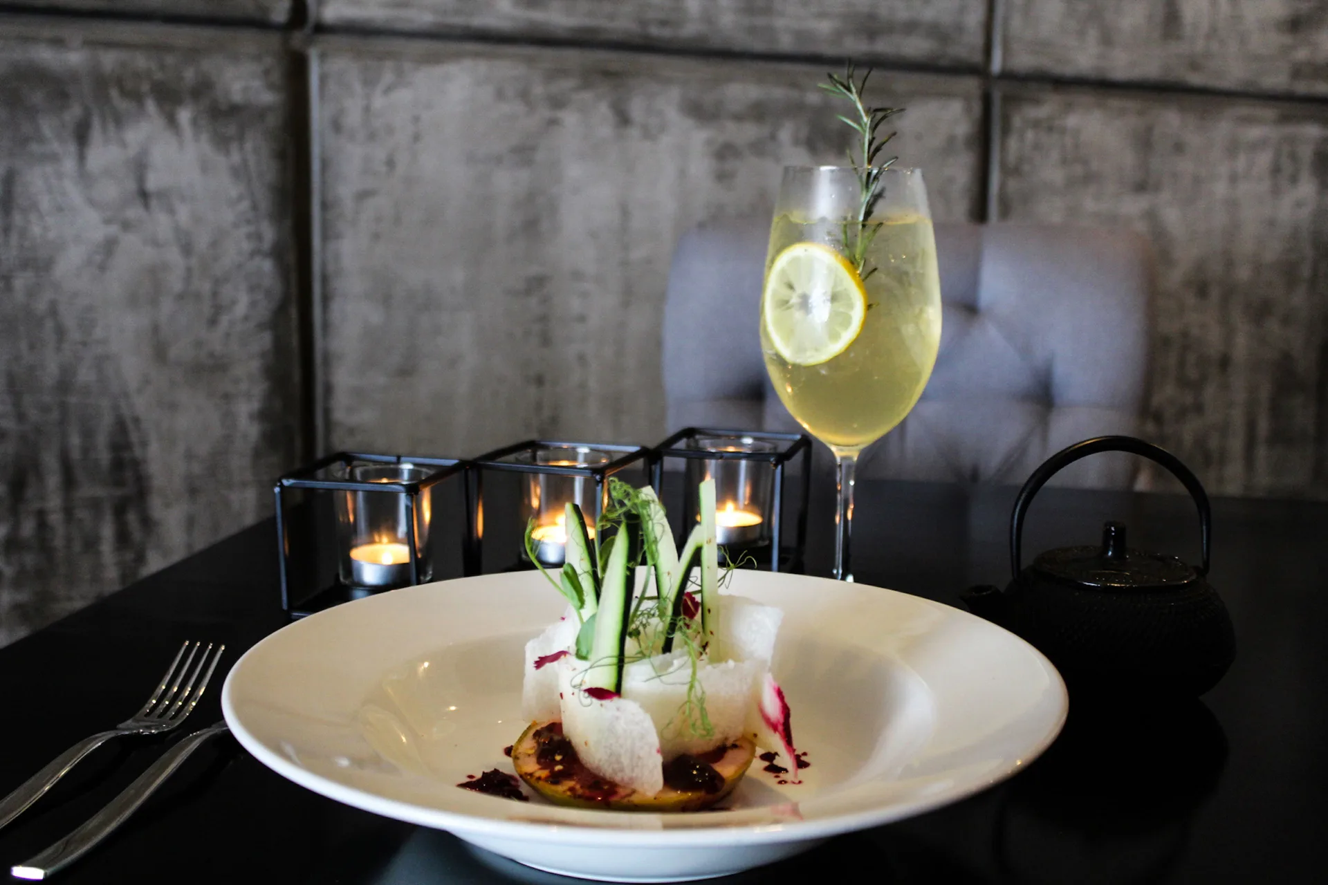 Plated appetizer with a citrus drink and candlelight at The Fives Beach Hotel.
