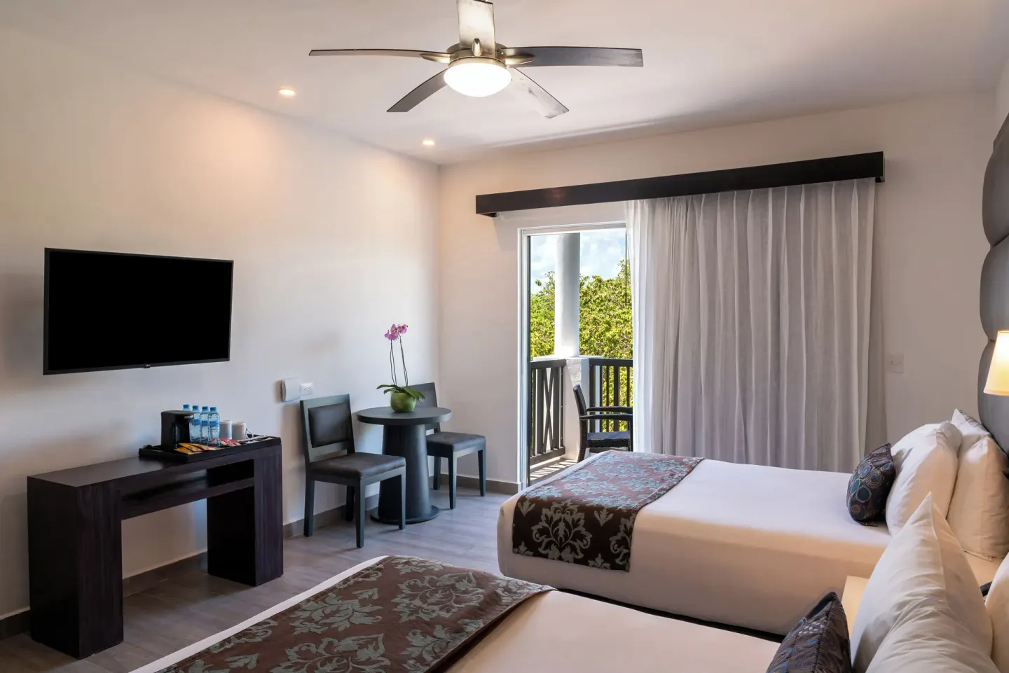Deluxe Room with two beds, TV, table and balcony at The Fives Beach Hotel.