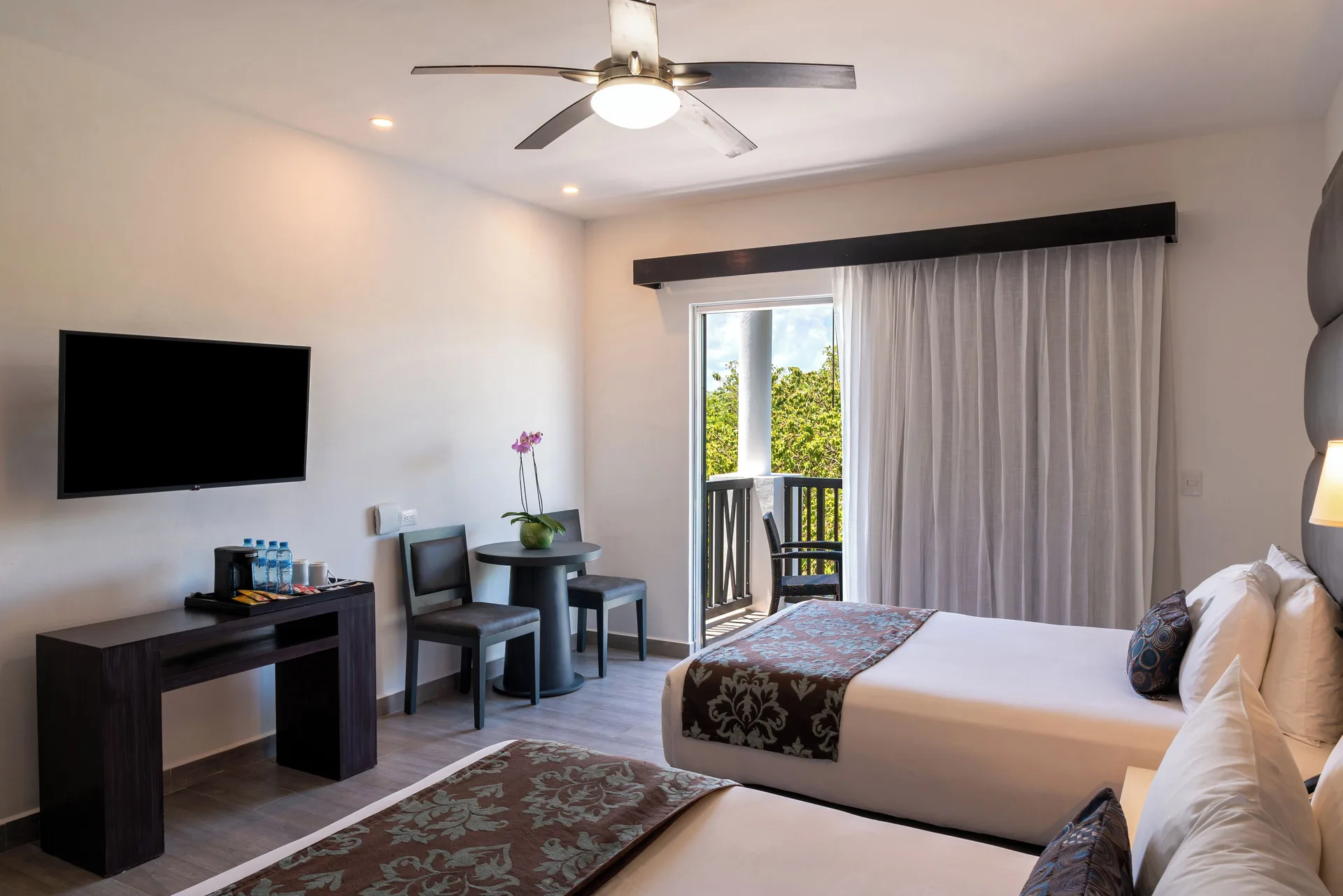 Deluxe Room with two beds, TV, table and balcony at The Fives Beach Hotel.