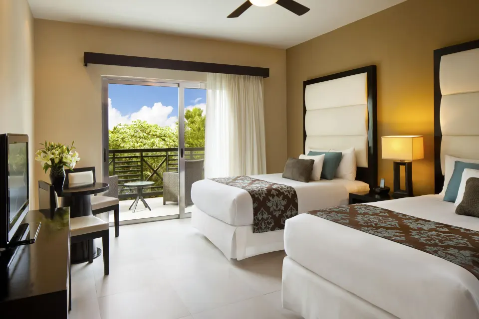 Deluxe Room with two beds, balcony doors and sitting area at The Fives Beach Hotel.