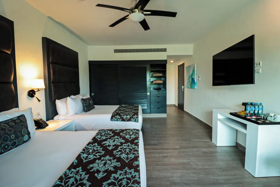Deluxe Room with two beds, wall TV and open closet at The Fives Beach Hotel.
