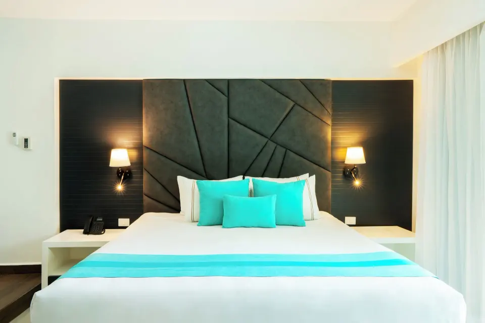 One Bedroom Penthouse Suite king bed with turquoise pillows at The Fives Beach Hotel.