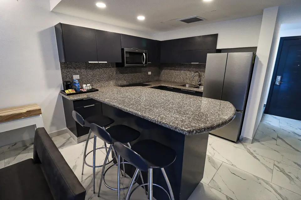 One Bedroom Penthouse Suite kitchen with granite counter and stools at The Fives Beach Hotel.